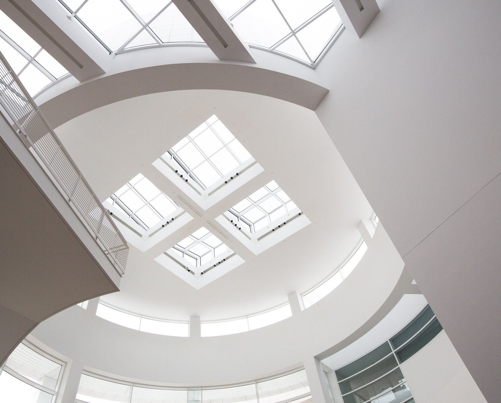 Elegant modern ceiling with geometric skylights in a bright white building interior.