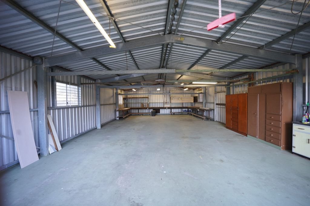 Empty industrial garage with metal walls and concrete floor ready for renovation or use.