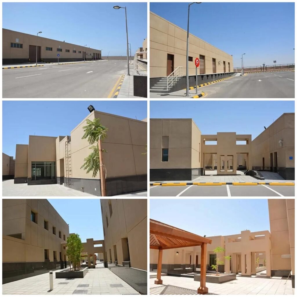 Sand-toned modular concrete institutional buildings with asphalt access roads and pedestrian courtyards at the Ministry of Interior Border Guard complex in Yanbu.